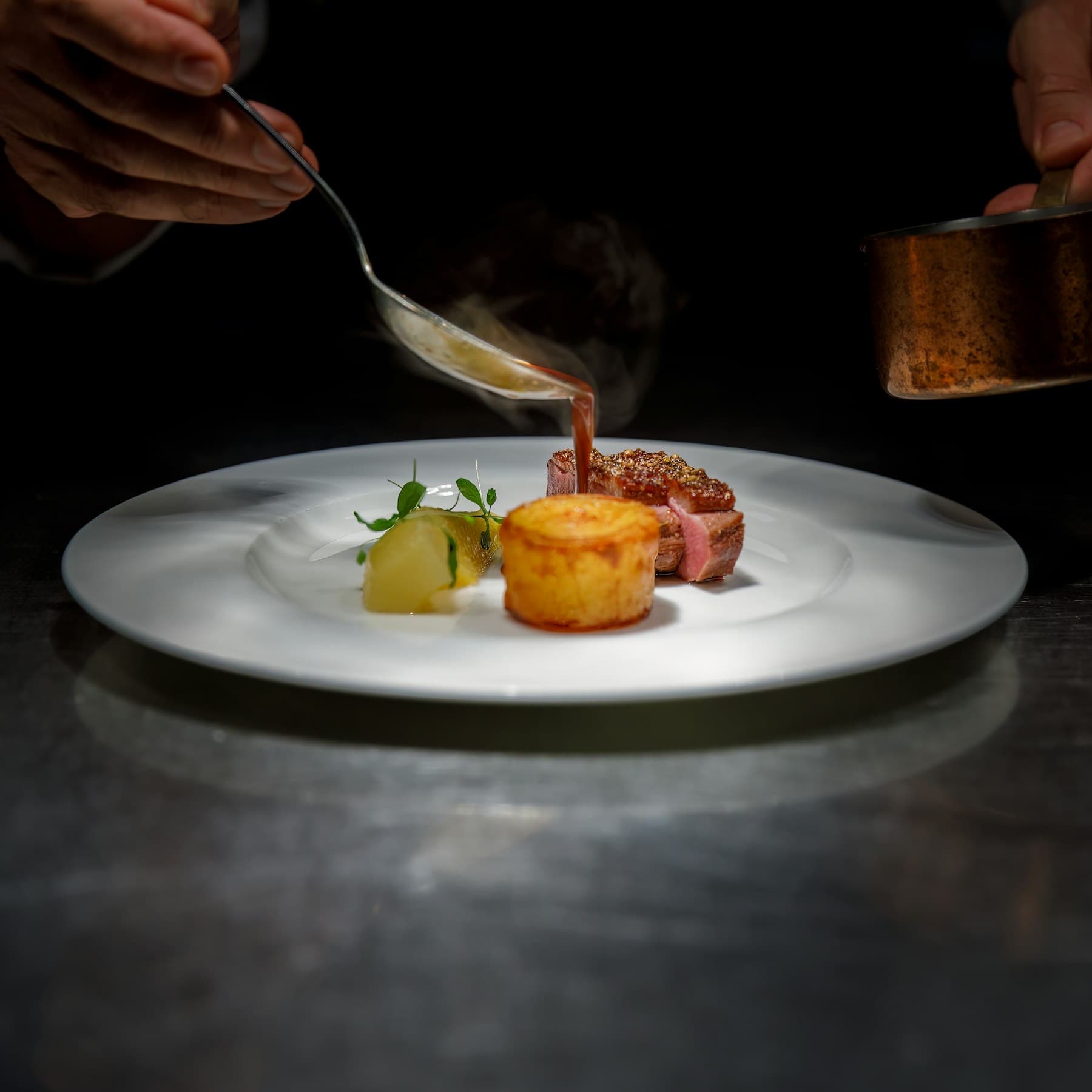 Un chef nappe une assiette au passe